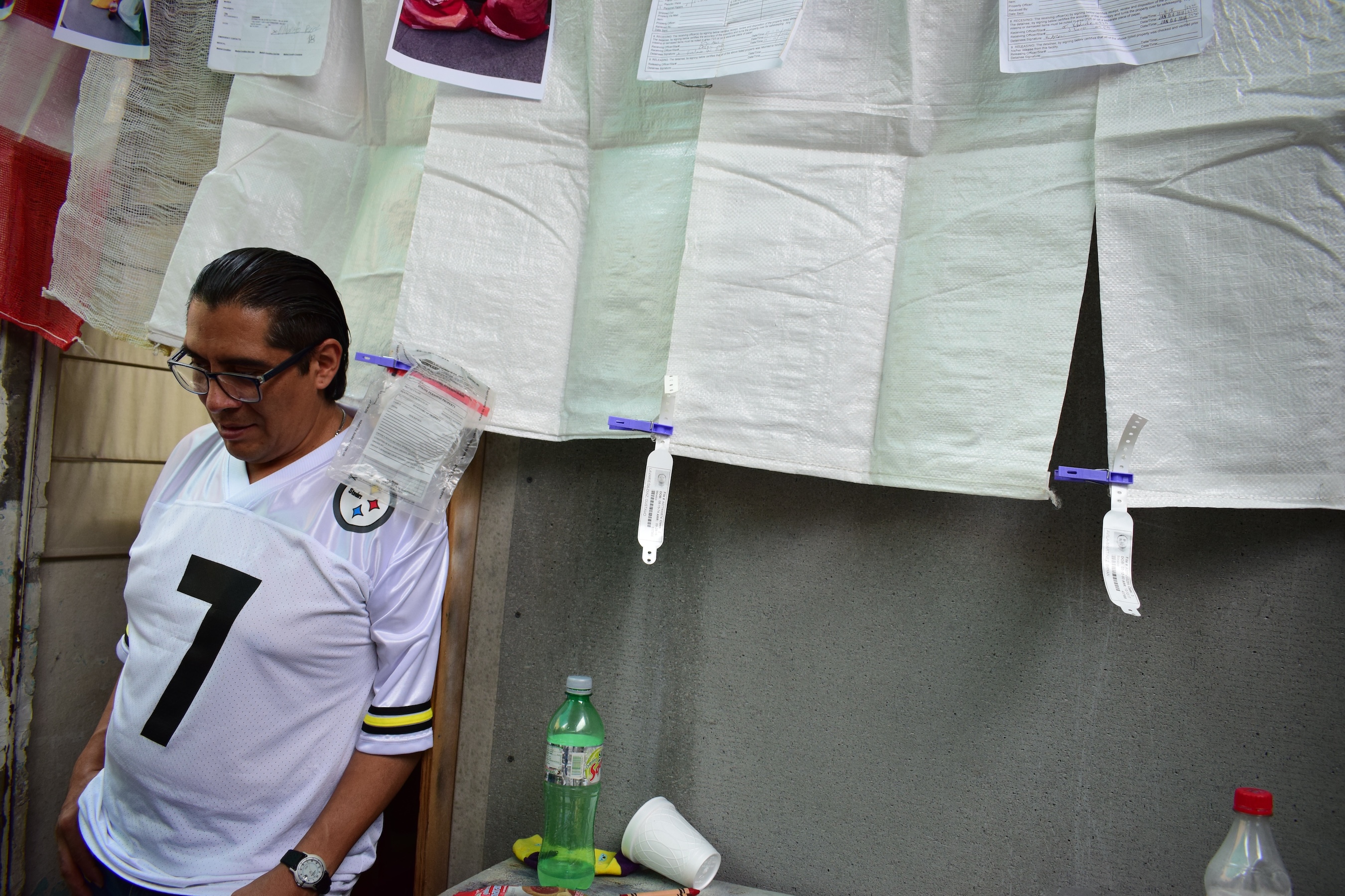 Interviewee David stands in front of an exhibit of sacks given to those who are deported in which to carry their things and copies of deportation papers.