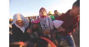Woman and man carrying injured person away from the border.